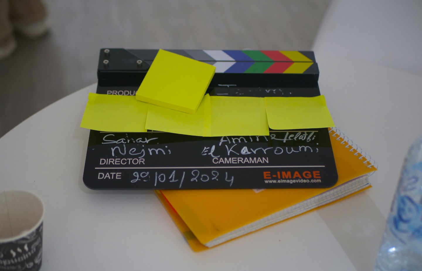 Film clapperboard with sticky notes resting on a notebook.