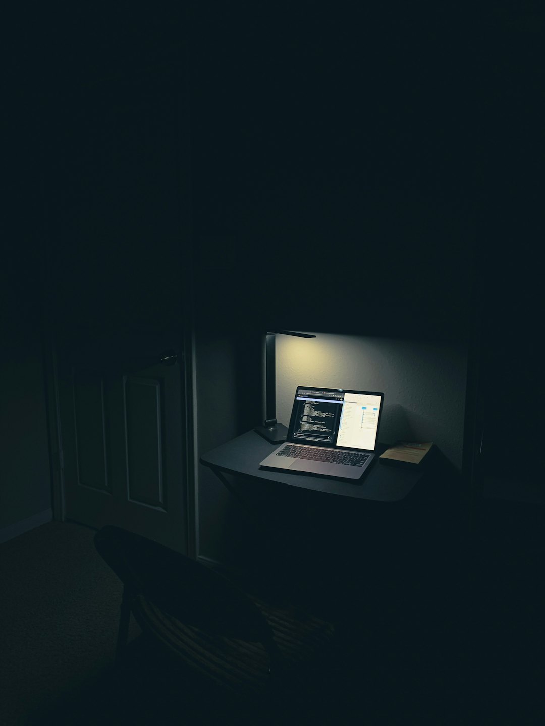A laptop screen displays programming code on a desk.