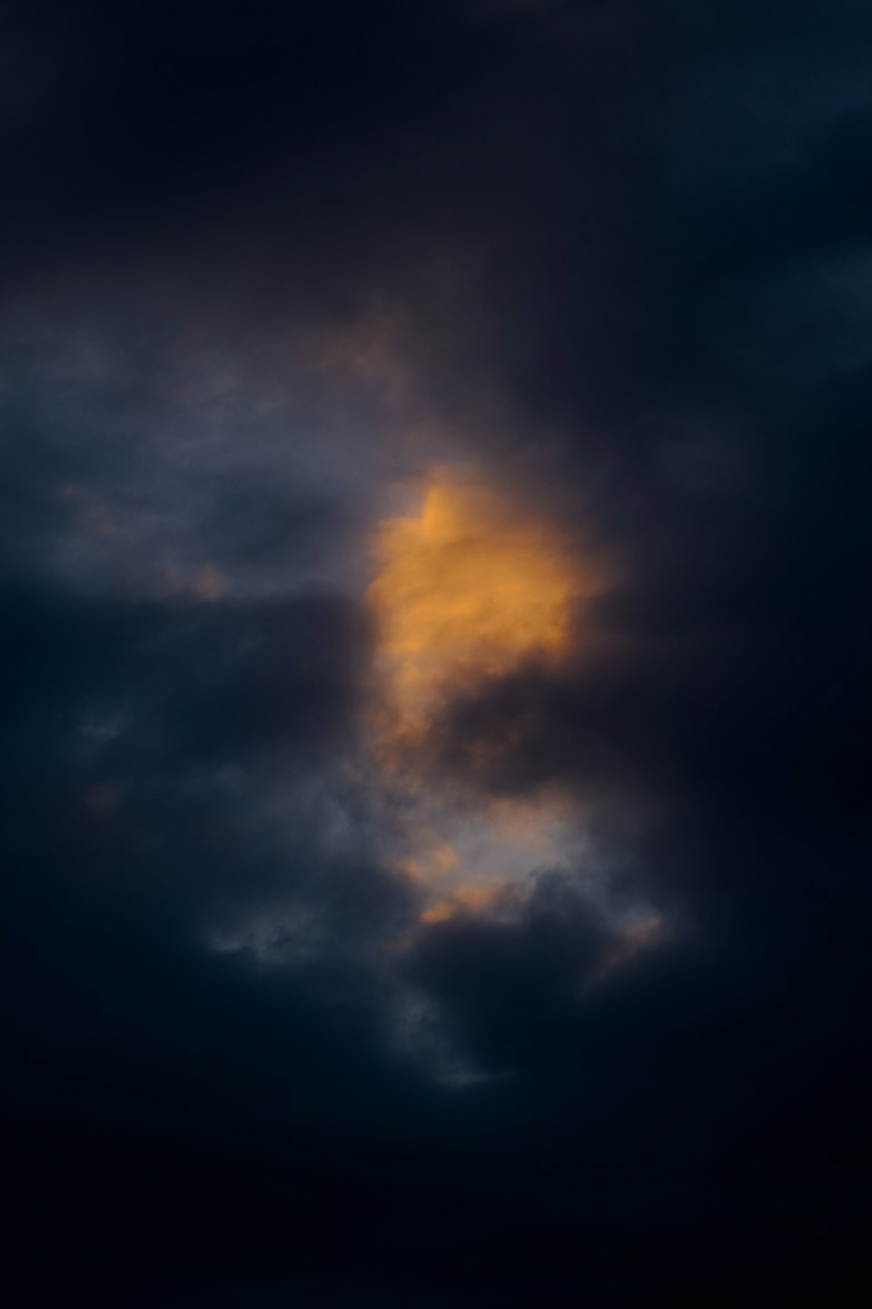 Dark storm clouds with a bright golden light breaking through.